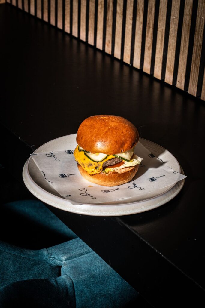 Diego's burger met cheddar, augurken en sla op een bord